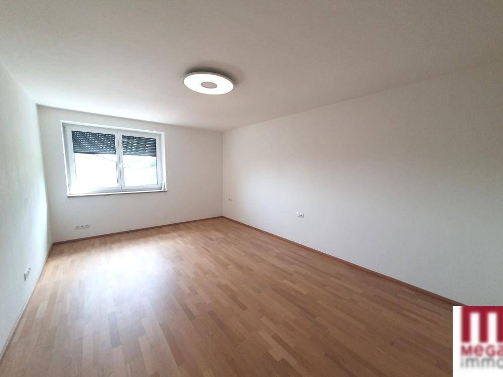 Helles Schlafzimmer mit Holzboden und großem Fenster, bereit zur individuellen Einrichtung.