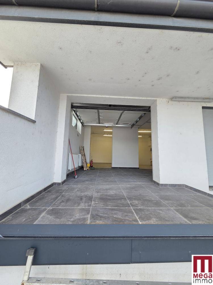 Überdachter Außenbereich mit Fliesenboden und Blick in einen hellen Innenraum.