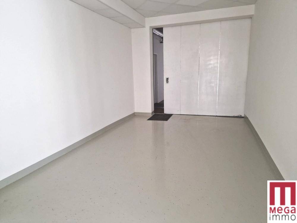 Leerer Raum mit hellem Vinylboden und einer großen Schiebetür, ideal für Büro oder Lager.