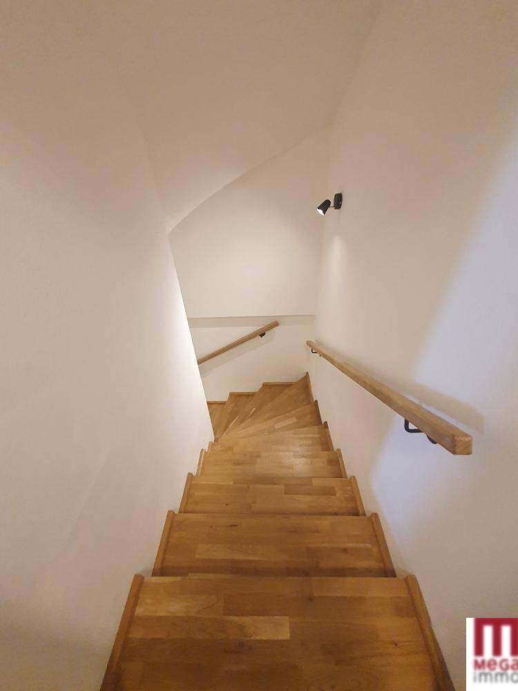 Helle Holztreppe mit Geländer, die zu den oberen Etagen des Hauses führt.