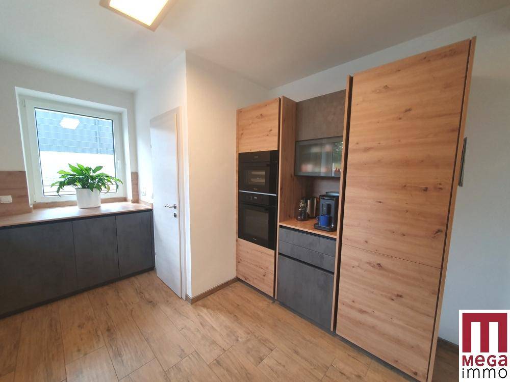 Hochwertige Einbauküche mit Holz- und Anthrazitfronten, integrierten Geräten und viel Stauraum.