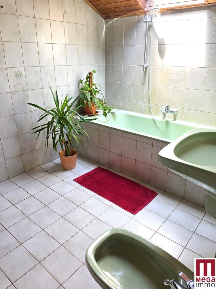 Badezimmer mit Badewanne, Waschbecken und Bidet in Pastellgrün, mit Dachfenster.