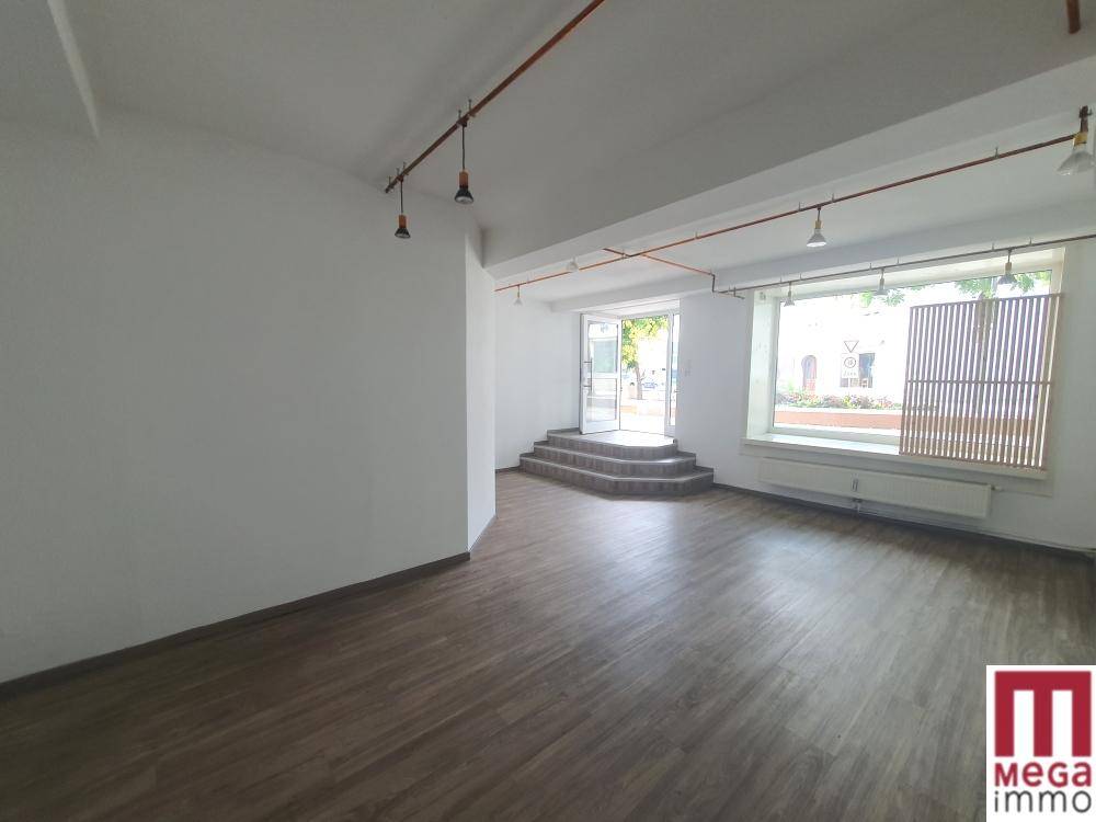 Geräumiger Gewerberaum mit Stufen zum Eingang und einem großen Fensterbereich.