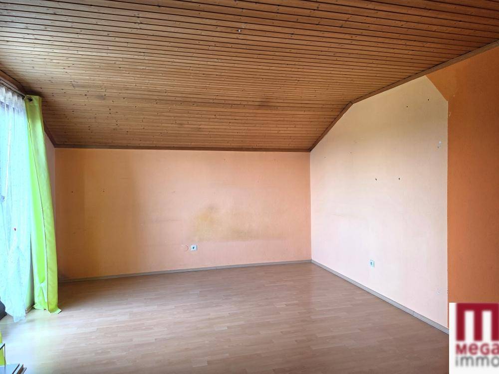 Geräumiges Zimmer mit Dachschräge, Holzbalkendecke und Laminatboden.