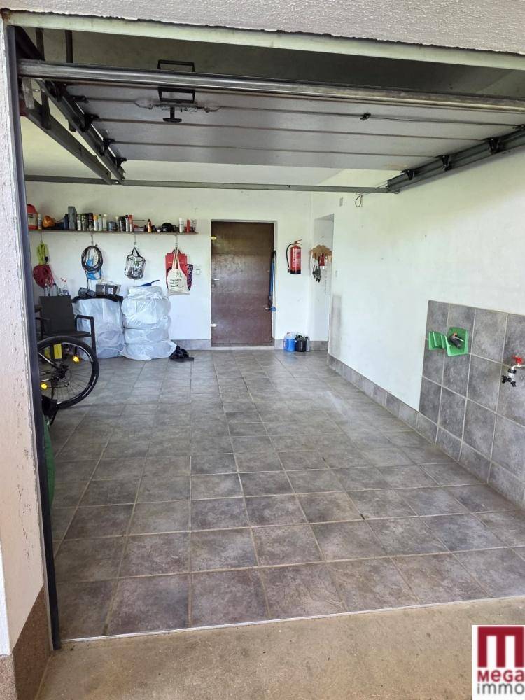 Geräumige Garage mit Fliesenboden, Stauraum und Zugang zu weiteren Räumen im Haus.