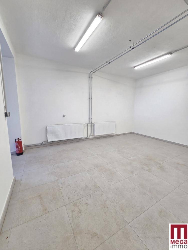 Heller und geräumiger Raum mit Fliesenboden, Heizkörpern und einem Feuerlöscher.