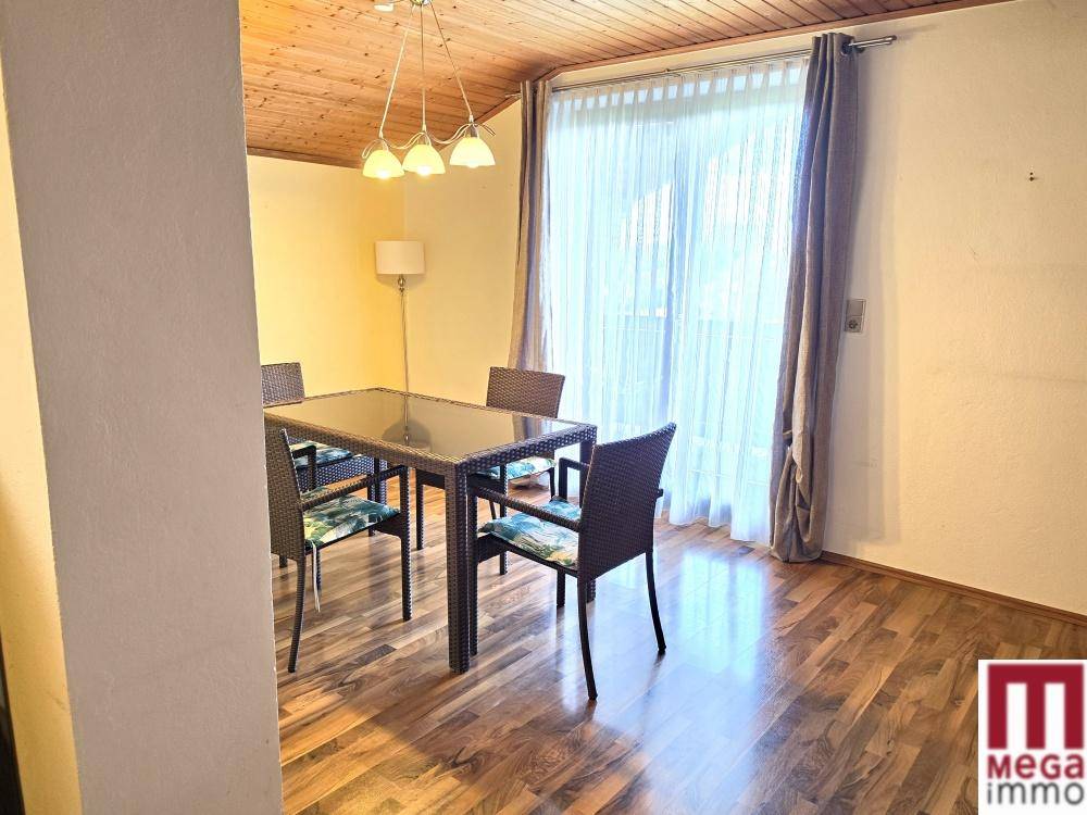 Heller Essbereich mit Holzbalkendecke und Zugang zu einem großen Fenster.