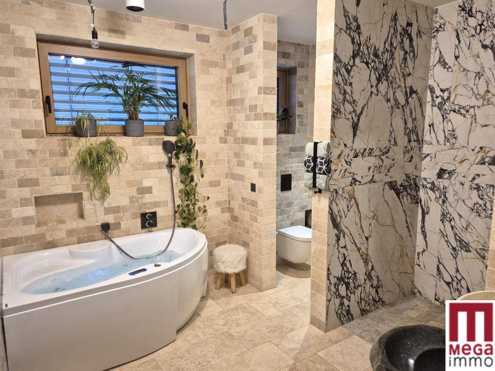 Geräumiges Badezimmer mit Whirlpool, Marmorwand und separatem WC-Bereich.
