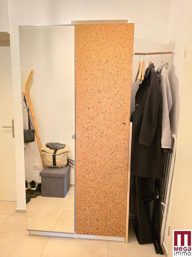 Flur mit großem Spiegel, Garderobe und Kork-Schrank.