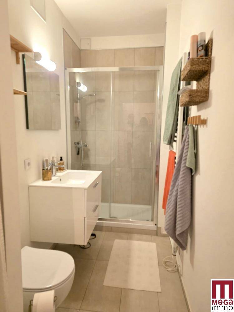 Modernes Badezimmer mit Duschkabine, Waschbecken und Wand-WC.