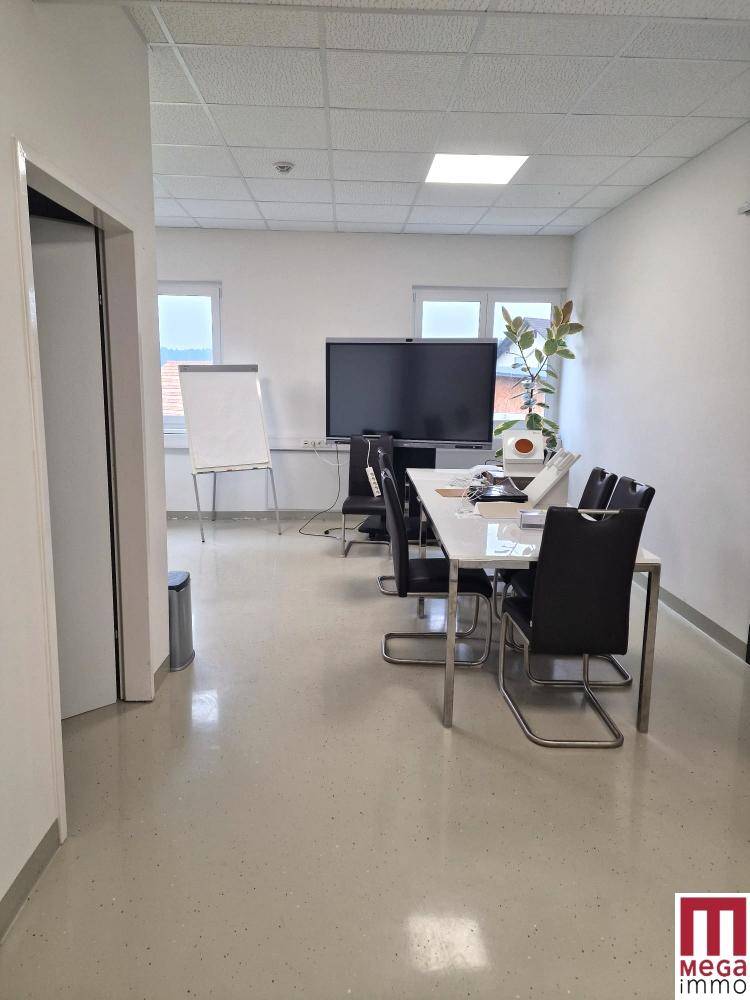 Geräumiger Konferenzraum mit großem Bildschirm, Besprechungstisch und Blick nach draußen.