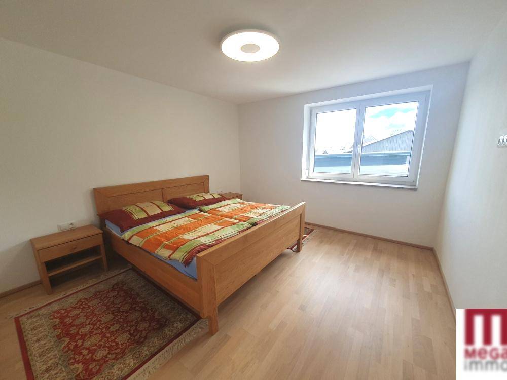 Gemütliches Schlafzimmer mit Doppelbett, Holzboden und großem Fenster, hell und einladend.