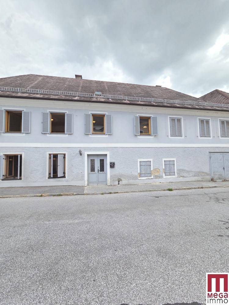 Vorderansicht des historischen Gebäudes mit hellblauer Fassade und vielen Fenstern.