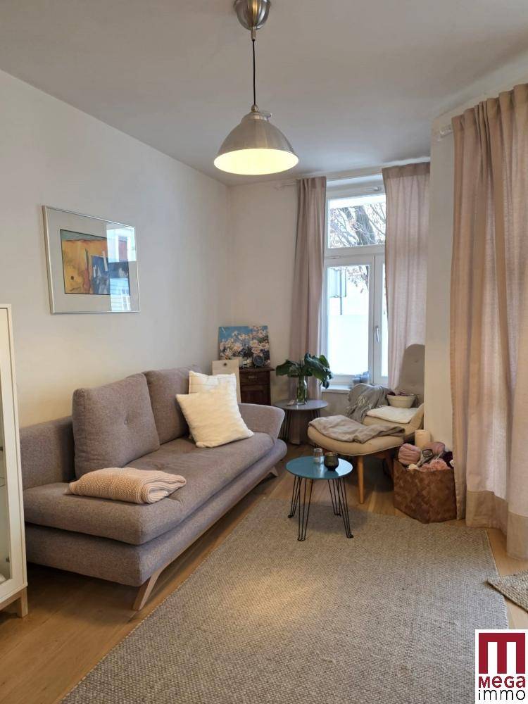 Gemütlicher Wohnbereich mit beigem Sofa, Teppich und viel Tageslicht.