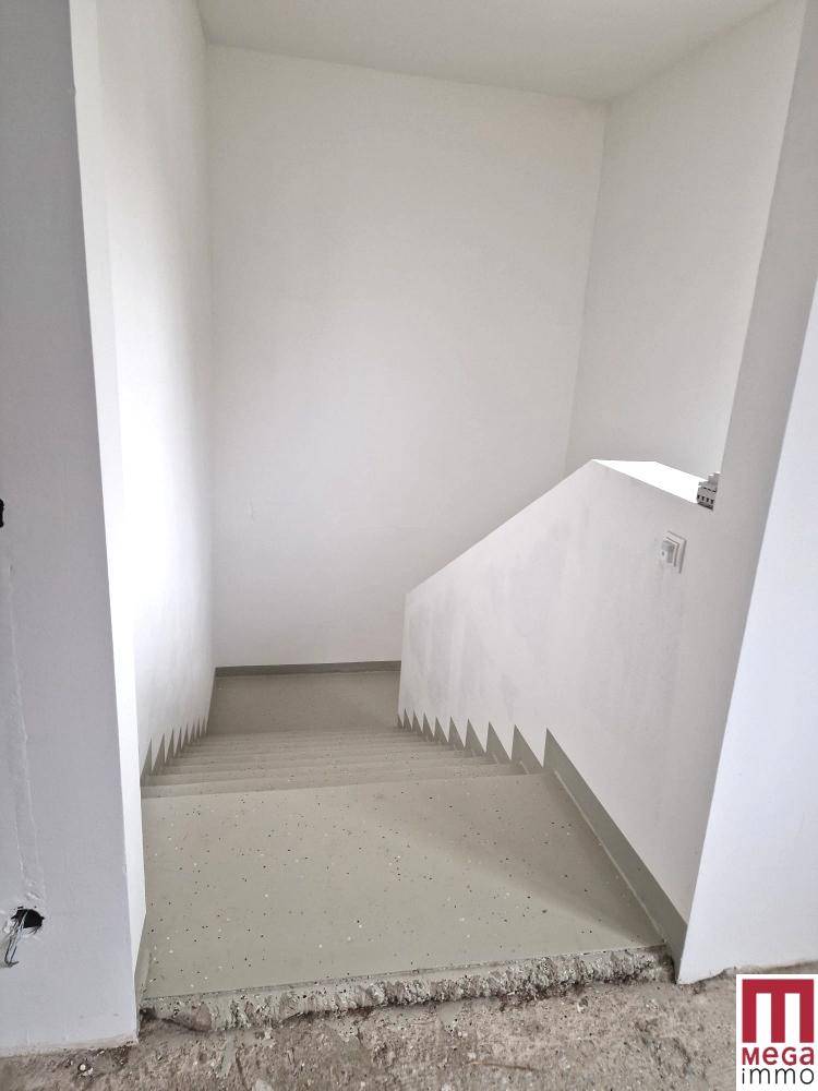 Schlichter Treppenaufgang mit hellgrauen Stufen und weißen Wänden in einem modernen Gebäude.