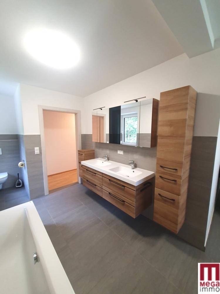Großes modernes Badezimmer mit Doppelwaschbecken, Spiegelschrank und grauen Fliesen.