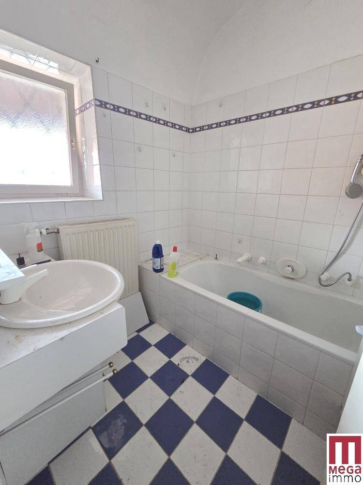 Badezimmer mit Badewanne, Waschbecken und blau-weiß kariertem Fliesenboden.