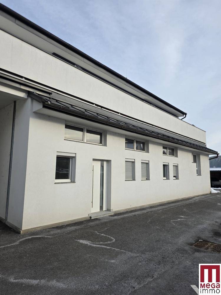 Seitenansicht eines modernen Gebäudes mit weißer Fassade und mehreren Fenstern.