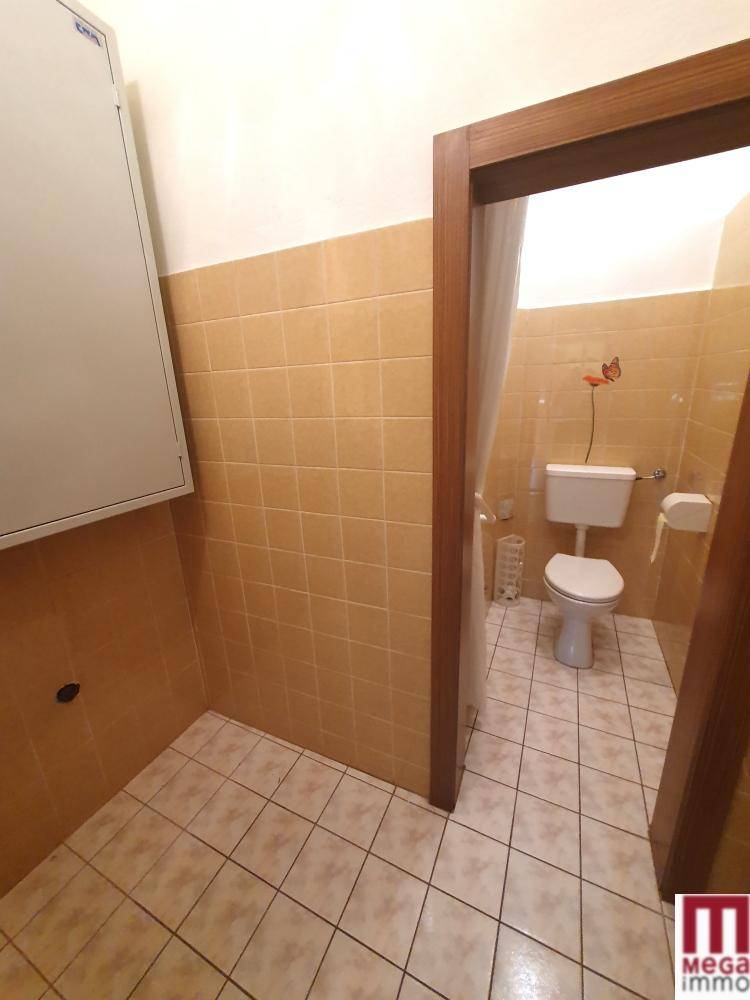 Separates WC mit beigefarbenen Fliesen und einfacher Toilette.
