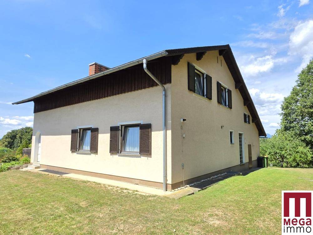 Seitenansicht des Hauses mit beiger Fassade, braunen Fensterläden und gepflegtem Rasen.