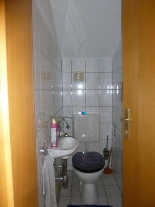 Kleines Gäste-WC mit Fliesen an Wänden und Boden sowie einem Waschbecken.