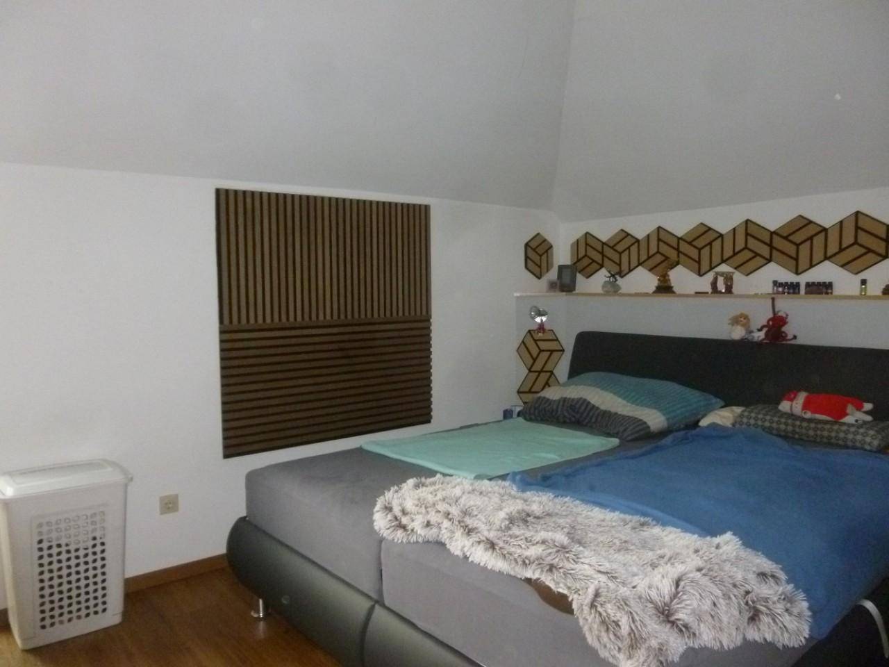 Schlafzimmer mit Dachschrägen, Holzboden und dekorativen Wandelementen.