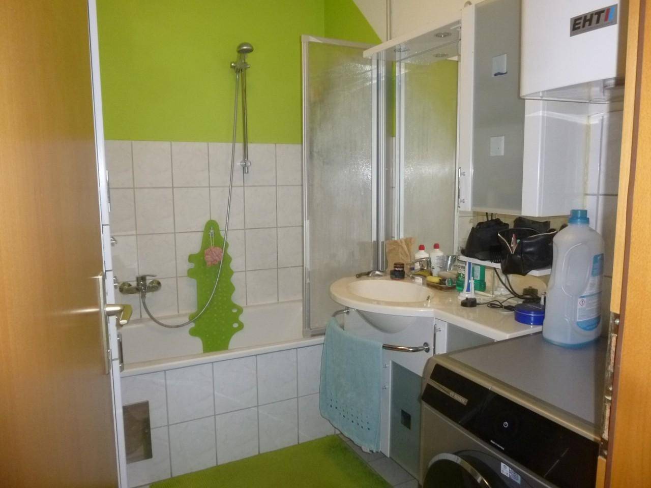Badezimmer mit Badewanne, Dusche, Waschbecken und Waschmaschine in lebendigem Grün.