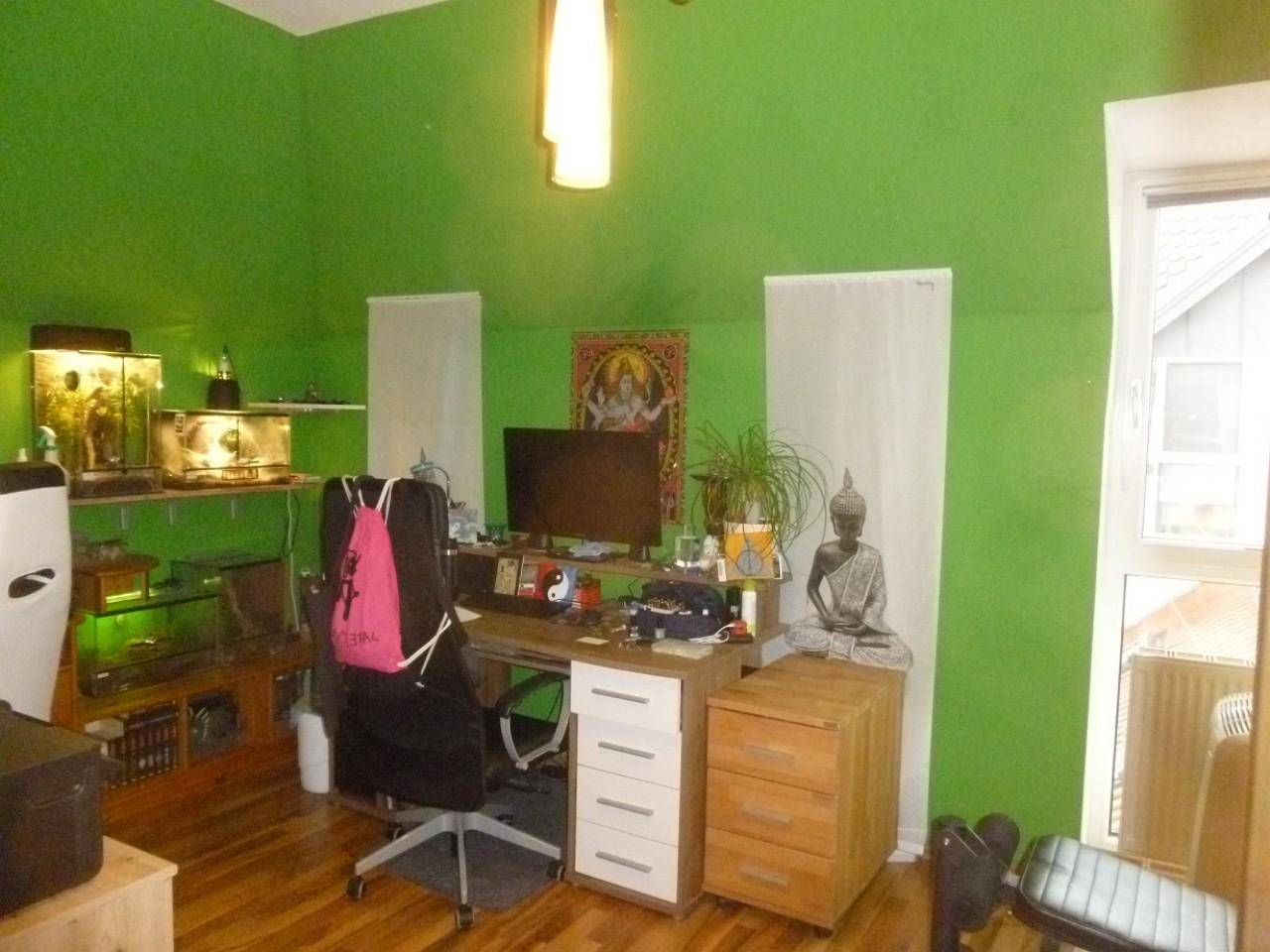 Arbeitszimmer mit grünen Wänden, Holzboden und Fenster für natürliches Licht.
