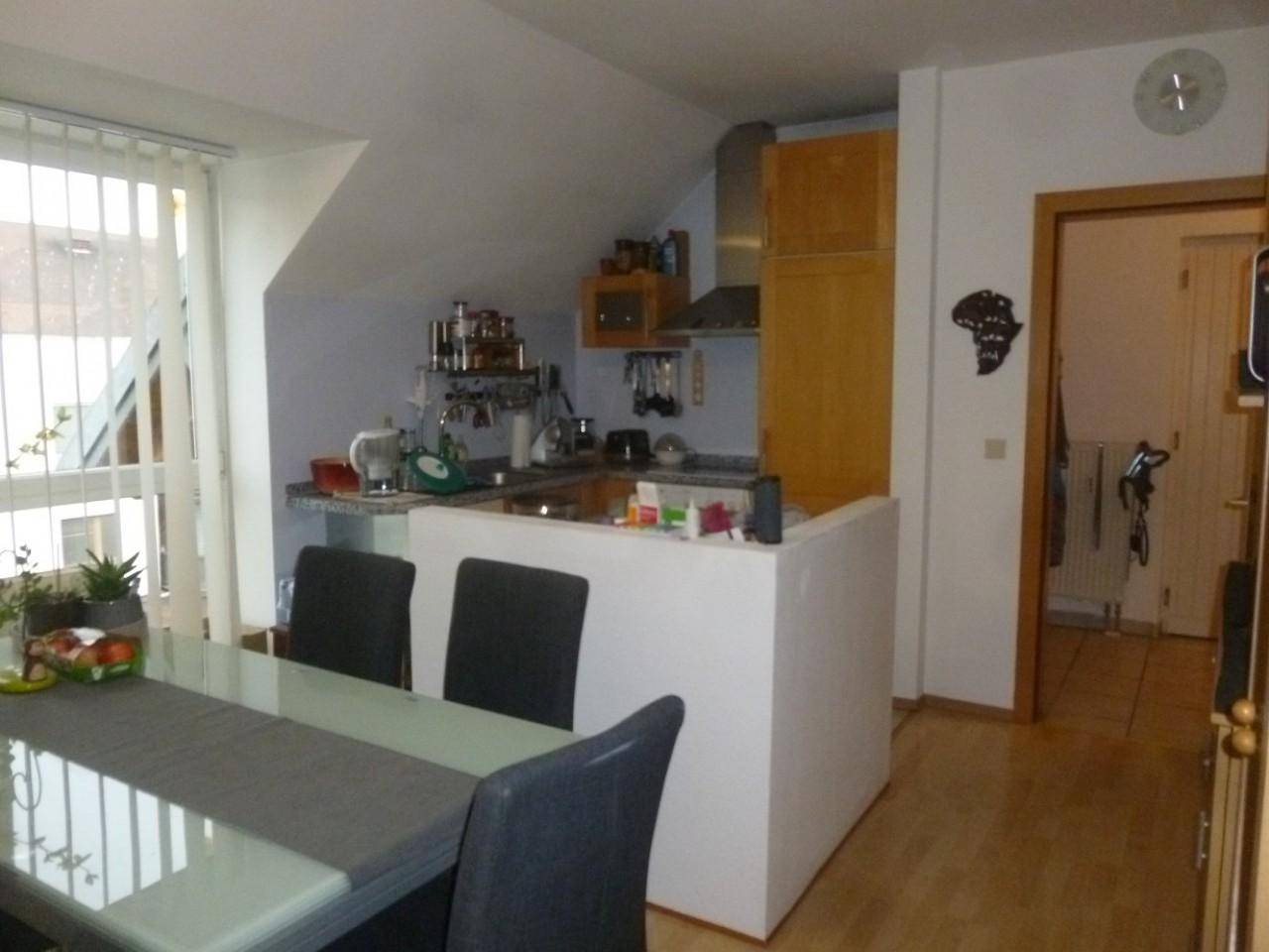 Offene Küche mit Holzelementen, Essbereich und Dachschrägen in einem hellen Raum.