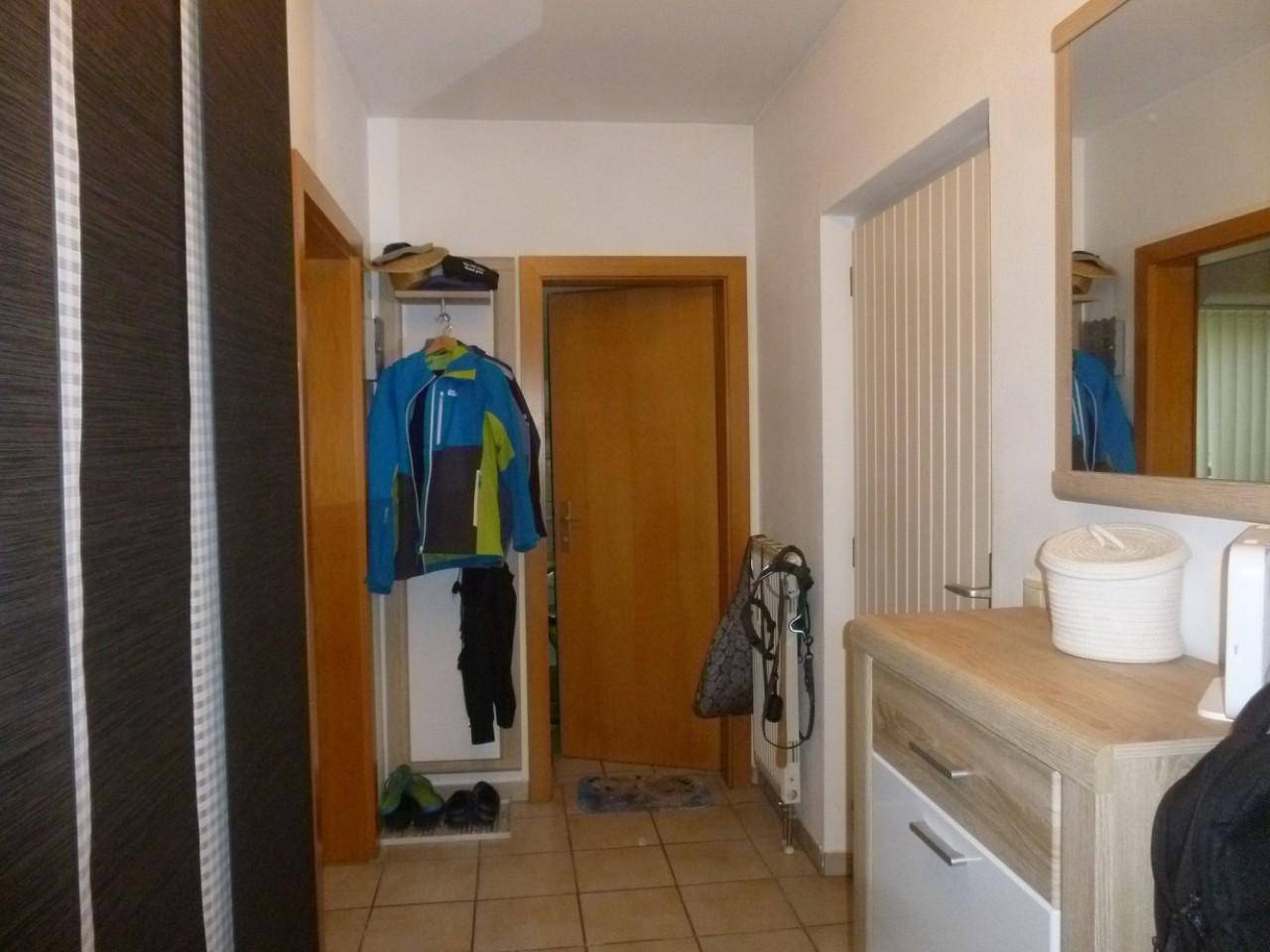 Heller Flur mit Fliesenboden, Garderobe und Spiegel.