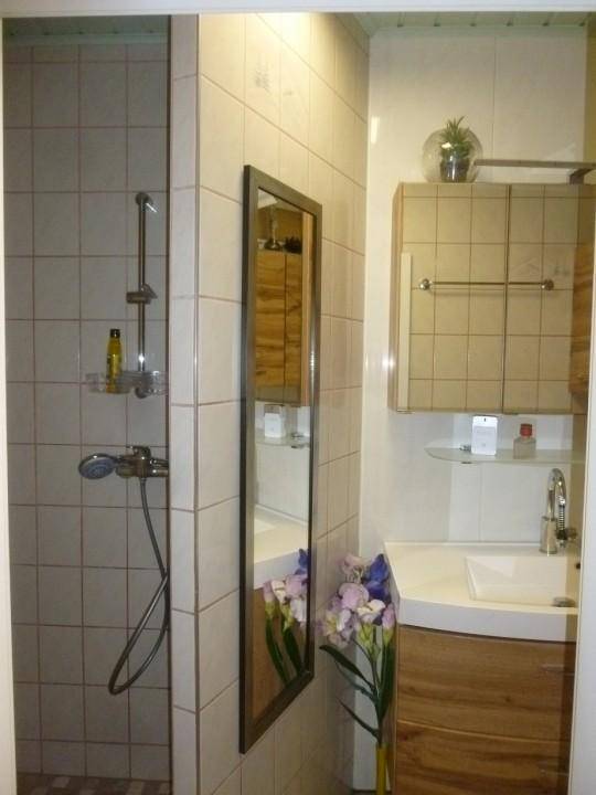 Helles Badezimmer mit Duschkabine, Waschtisch und Wandspiegel.