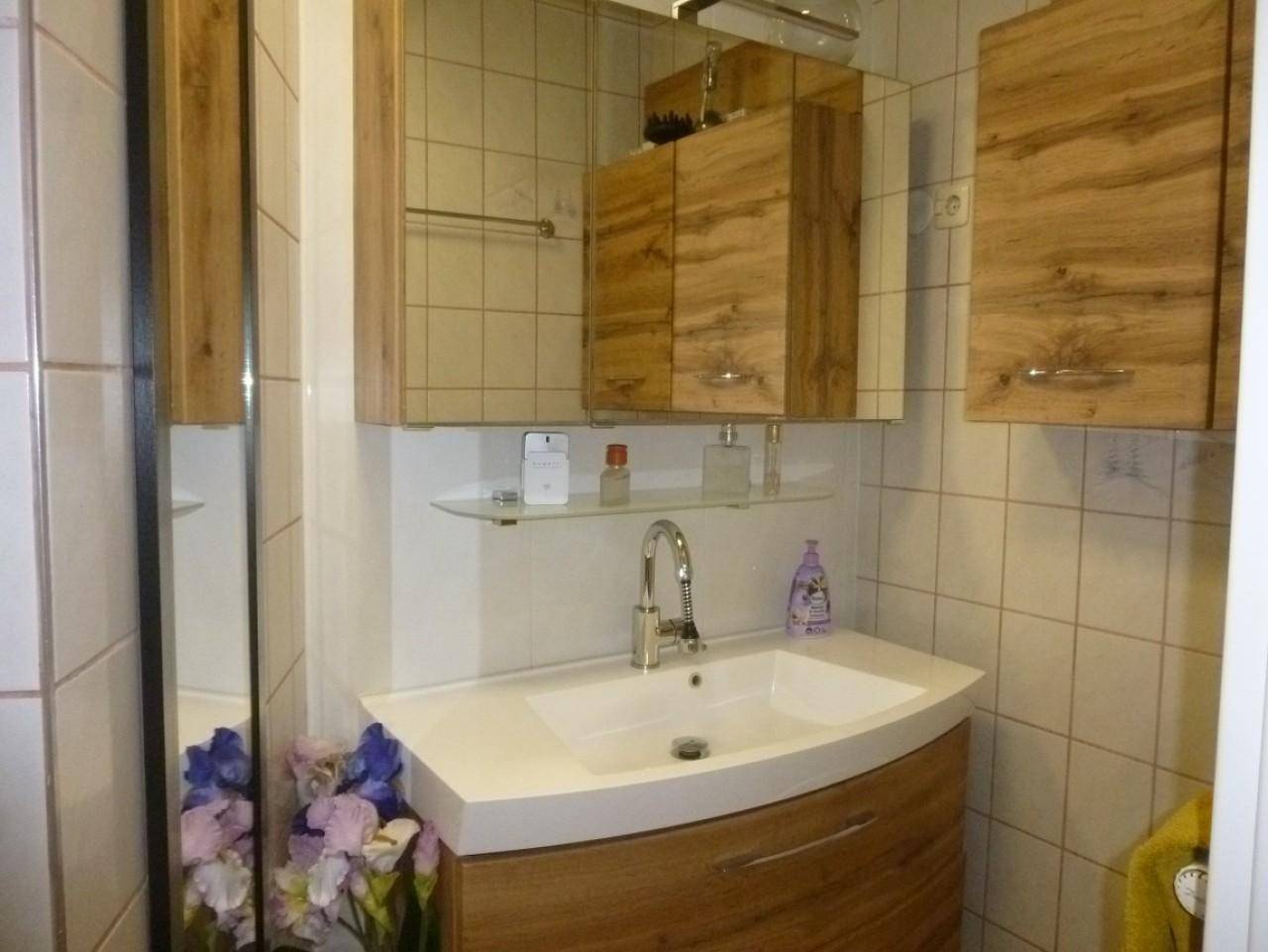 Badezimmer mit modernem Waschtisch, Spiegelschrank und hellen Fliesen.