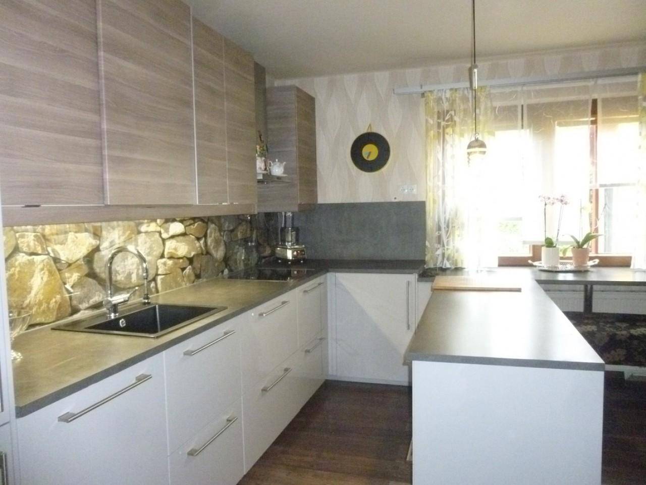 Moderne Küche mit hellen Schränken, Steinfliesen-Rückwand und Fenster mit Tageslicht.