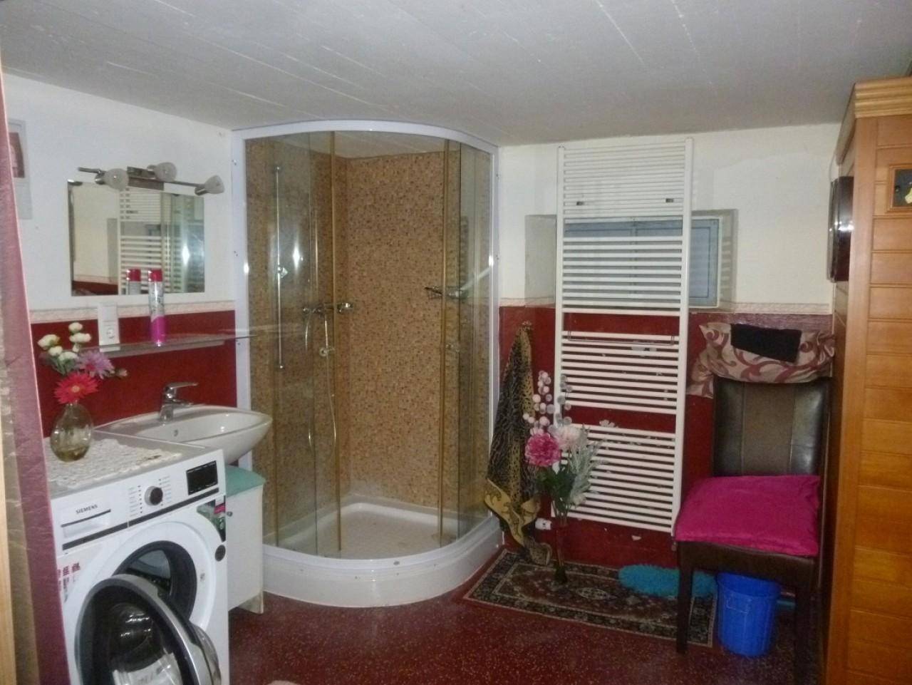 Badezimmer im Keller mit Duschkabine, Waschmaschine und beheiztem Handtuchhalter.