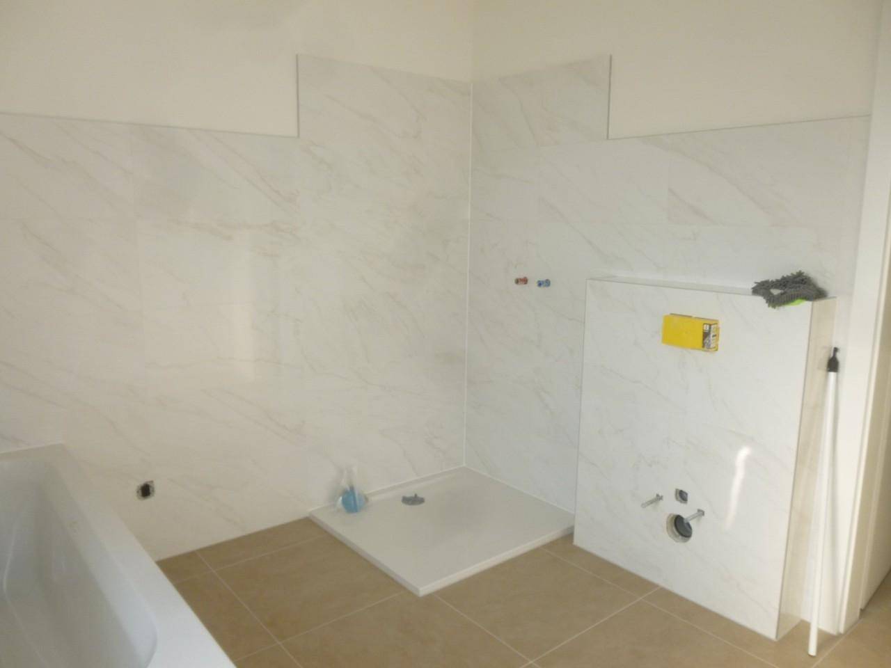 Badezimmer im Bau mit Duschwanne und Vorbereitung für Wand-WC.