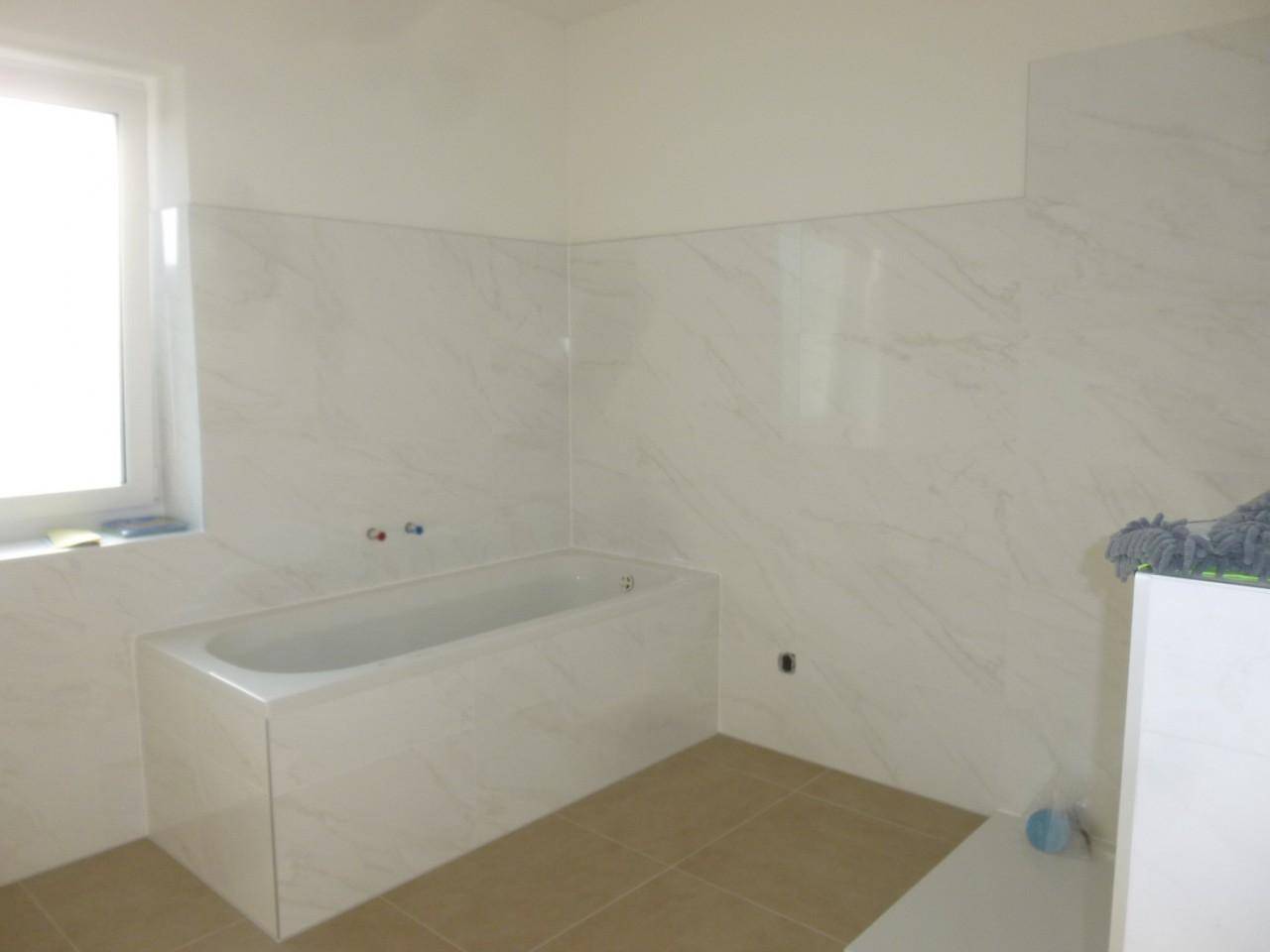 Badezimmer im Bau mit eingebauter Badewanne und hellen Marmorfliesen.