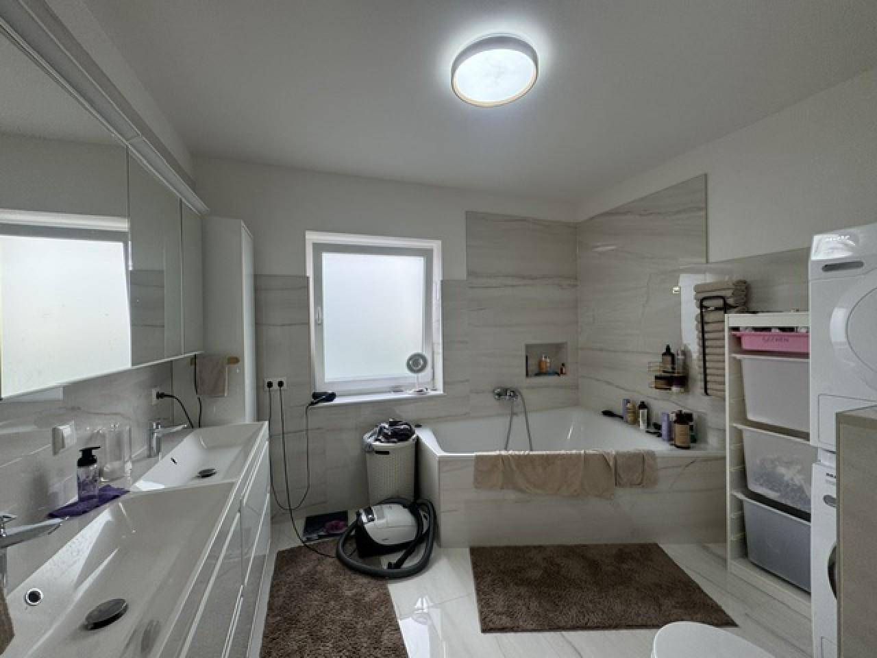 Modernes Badezimmer mit Doppelwaschbecken, Badewanne und Waschmaschinenanschluss.