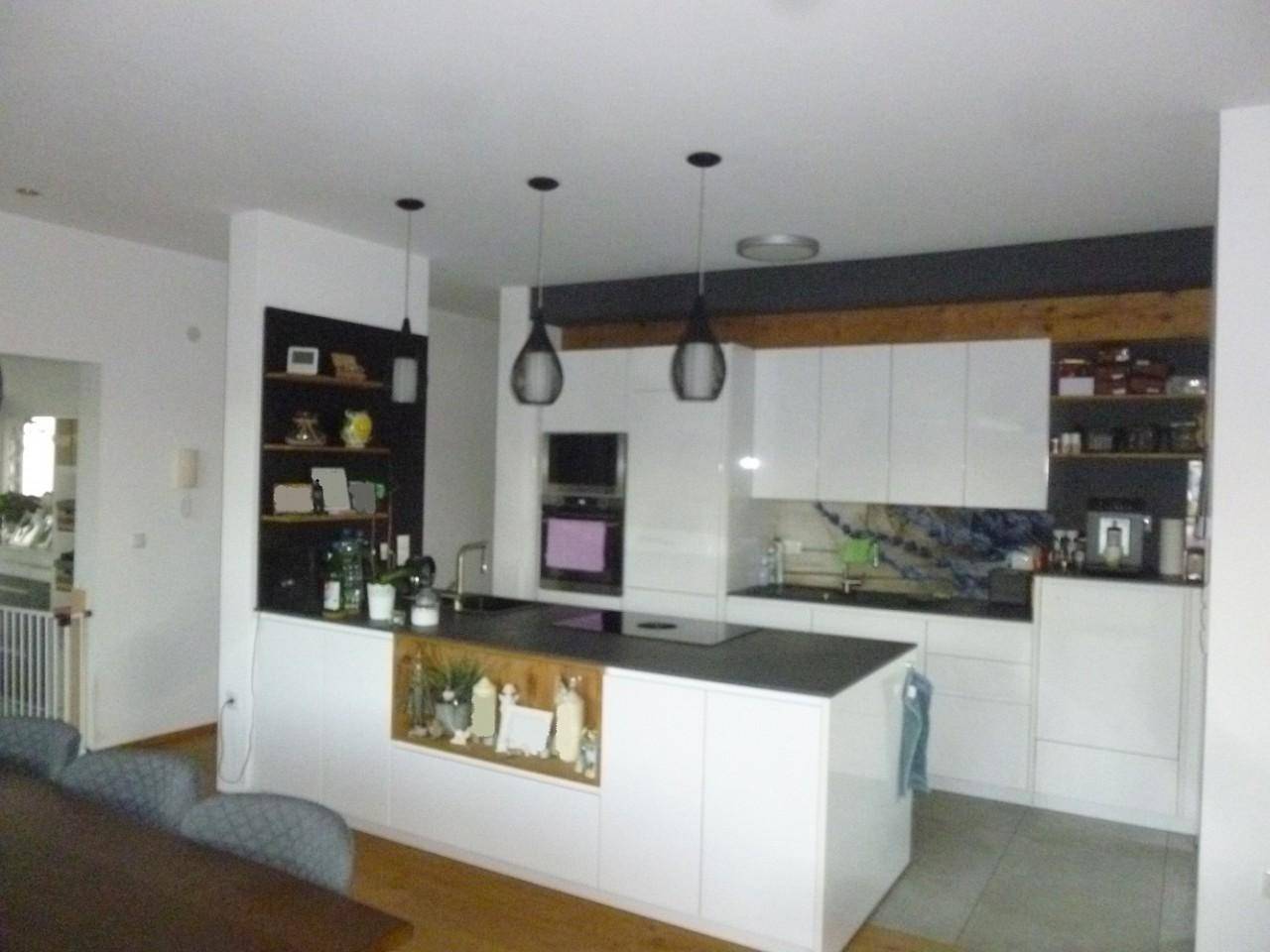 Moderne Einbauküche mit weißen Hochglanzfronten, Kochinsel und integrierten Geräten.