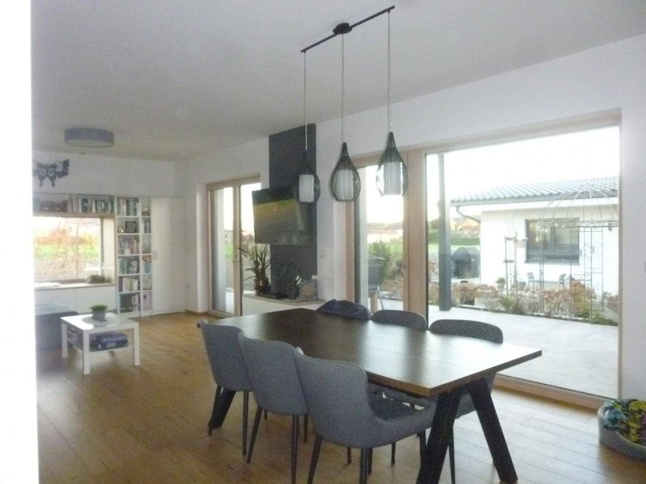 Geräumiger Essbereich mit Holztisch, modernen Stühlen und großen Schiebetüren zur Terrasse.