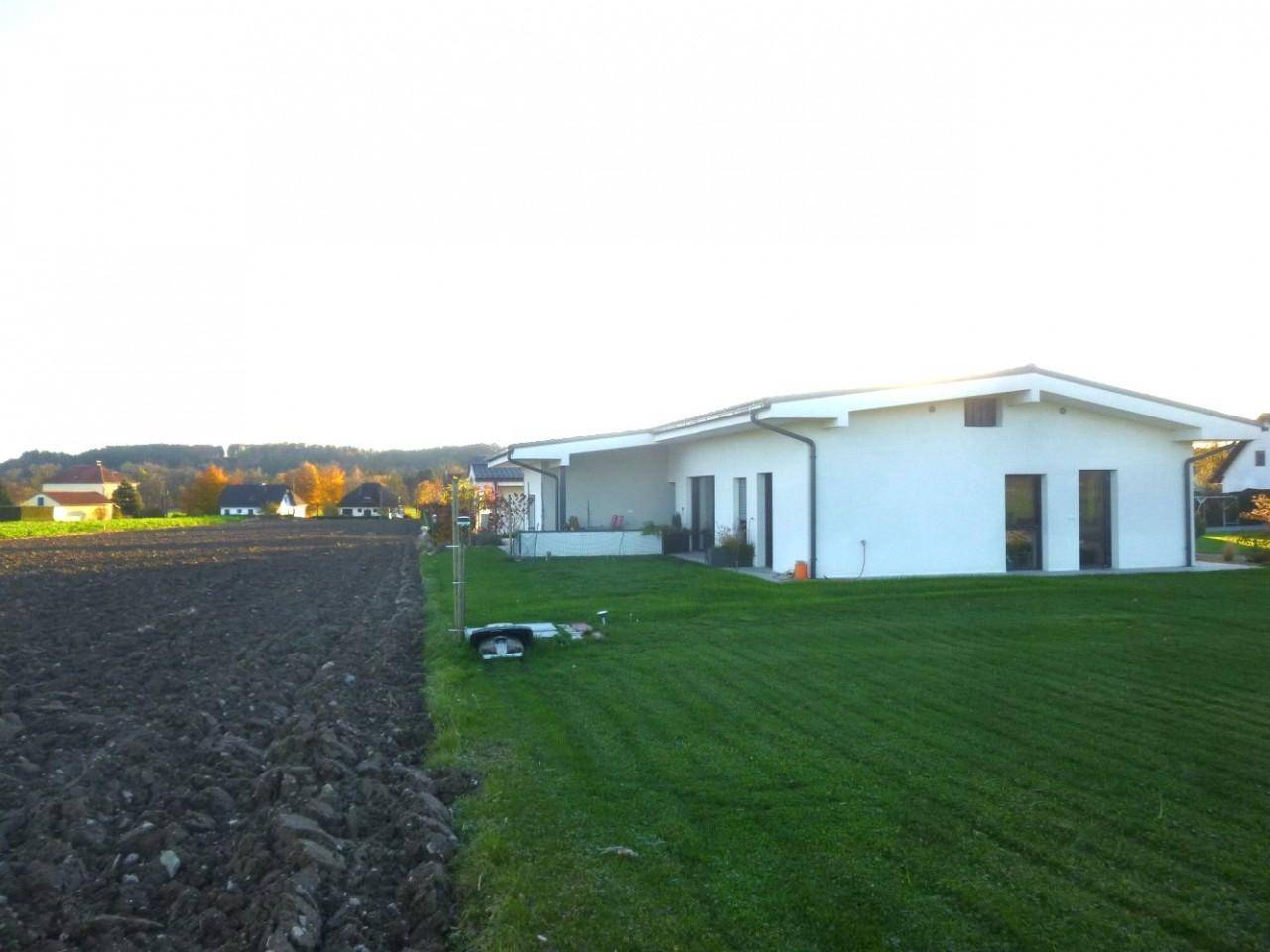 Modernes Einfamilienhaus mit gepflegtem Rasen und weitem Blick über Felder und Landschaft.