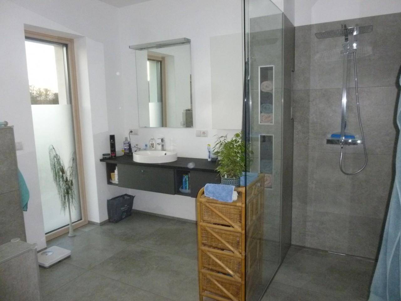 Helles Badezimmer mit begehbarer Dusche, modernem Waschtisch und großem Fenster.
