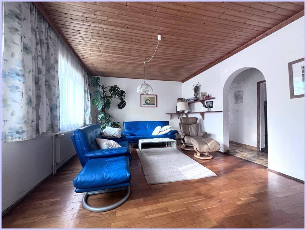 Gemütliches Wohnzimmer mit Holzboden, Holzdecke und blauen Ledersofas, die zum Entspannen einladen.