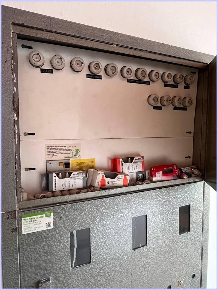Alter Sicherungskasten mit Keramiksicherungen, der die elektrische Installation des Hauses zeigt.