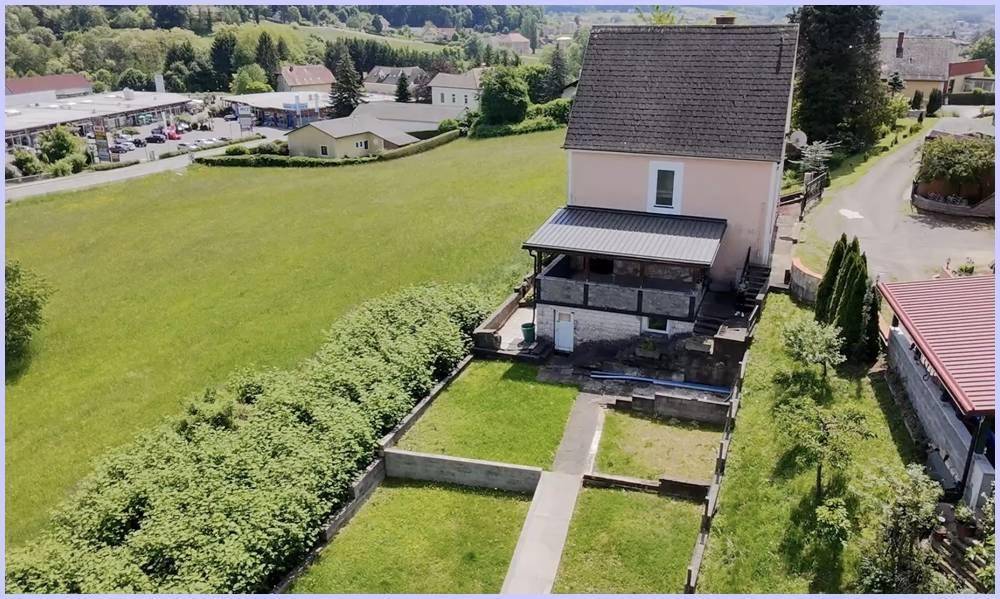 Hinteransicht des Hauses mit gepflegtem Gartenbereich und angrenzender Grünfläche.