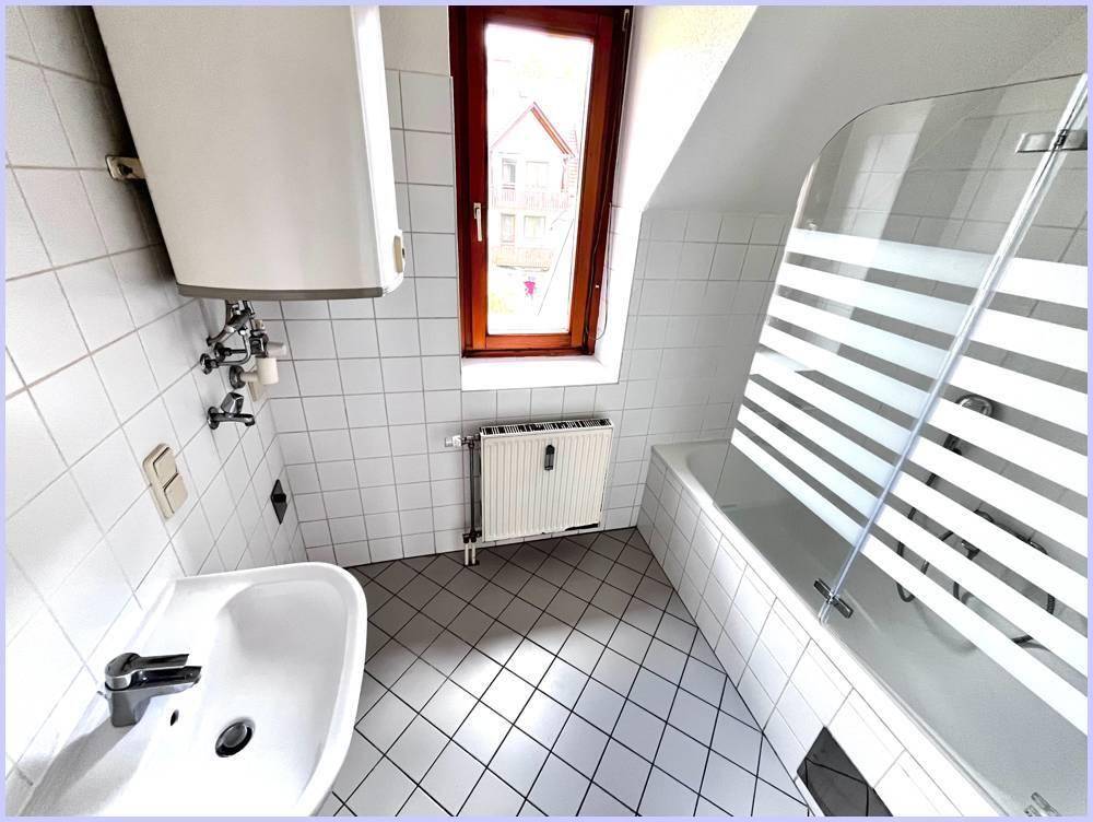 Badezimmer mit Waschbecken, Badewanne, Duschabtrennung und Fenster.