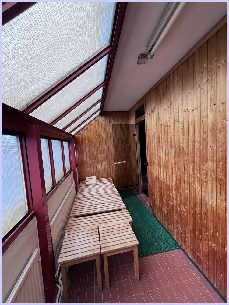 Heller Wintergarten mit Holzverkleidung und Sitzbänken, ideal zum Entspannen.