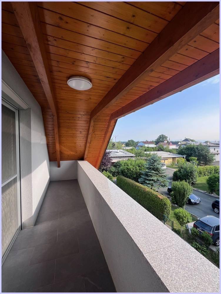 Überdachter Balkon mit Holzbalkendecke und Blick auf die umliegende Wohngegend.