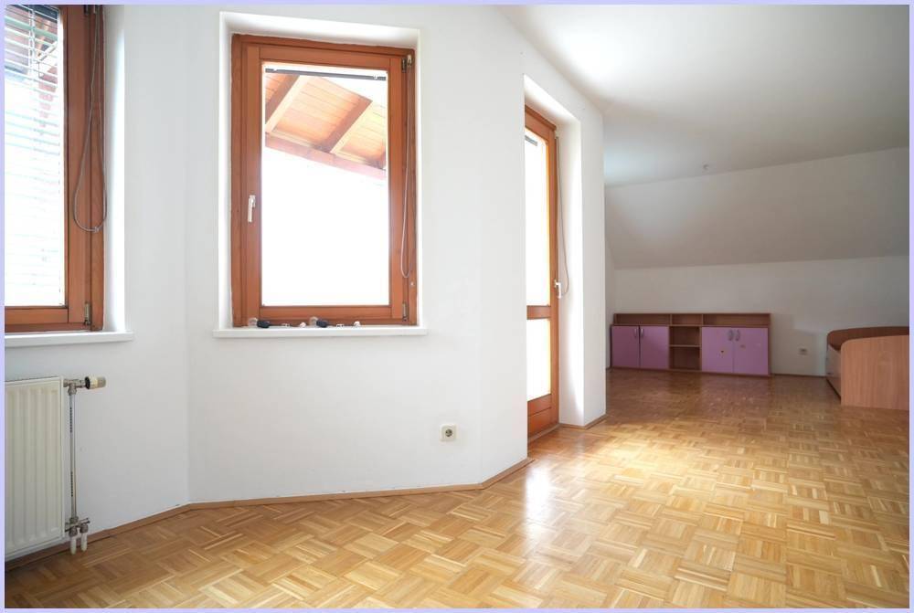 Lichtdurchfluteter Raum mit Parkettboden, großen Fenstern und Zugang zum Balkon.