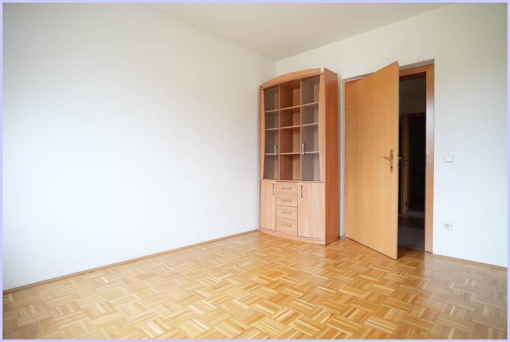 Heller Raum mit Parkettboden und einem Holzschrank, bereit zur individuellen Nutzung.
