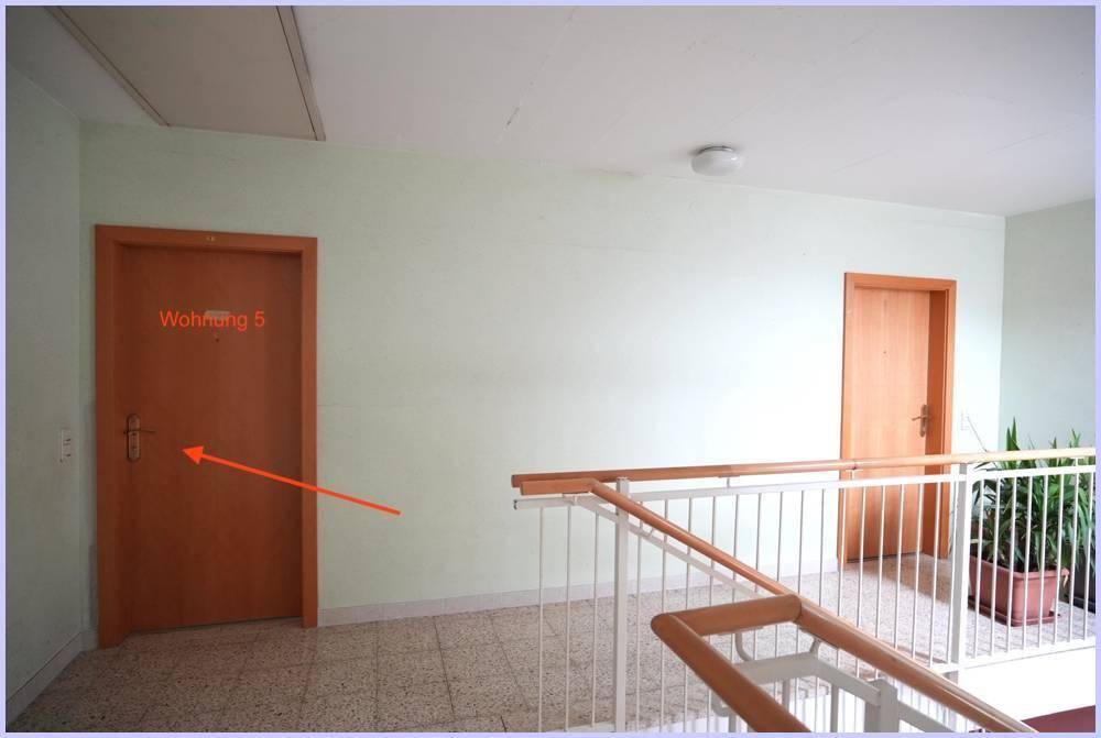 Treppenhaus mit hellem Fliesenboden und einer Tür mit der Aufschrift "Wohnung 5".